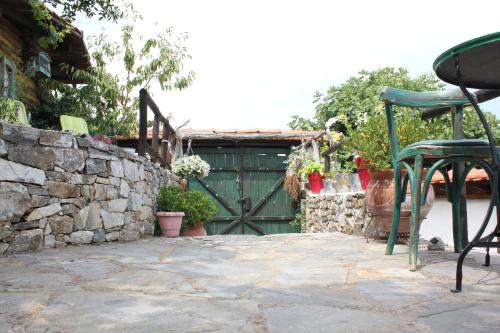 a patio with a green gate and a stone wall at Feggaropetra Inn Magic Mountain House in Palaios Panteleimon