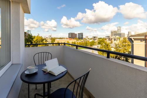 un tavolo e delle sedie su un balcone con un libro di Balcia Residence a Riga