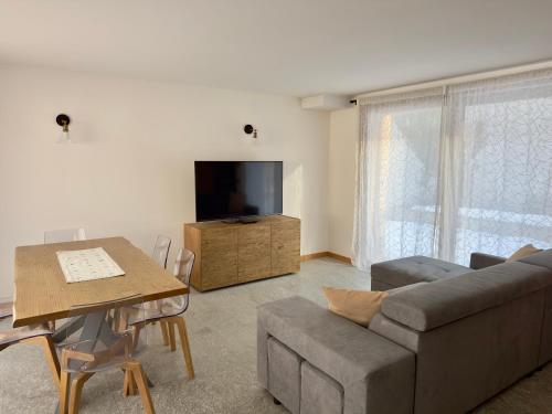 a living room with a couch and a tv and a table at Chalet Ski Home - Madesimo in Madesimo