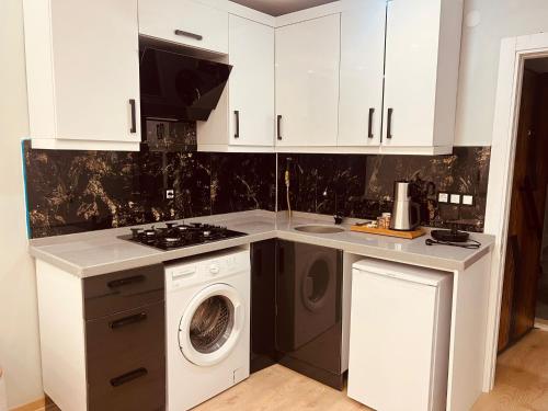 a kitchen with white cabinets and a washer and dryer at Bediroğlu apart in Arnavutköy