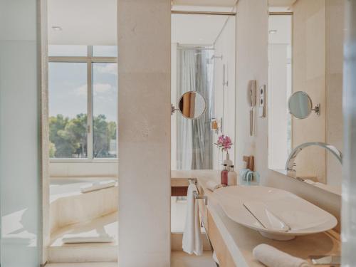 een witte badkamer met een bad en een wastafel bij Aguas de Ibiza Grand Luxe Hotel - Small Luxury Hotel of the World in Santa Eularia des Riu