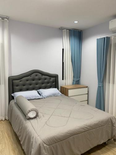 a bedroom with a large bed with blue curtains at Alayah บ้านเดี่ยวสองชั้น ธาดาดิโอเอซิส in Ban Krok Khi Nu