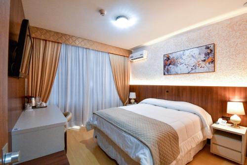 a hotel room with a bed and a window at Hotel Jaragua in Joaçaba