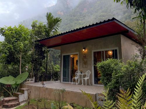 una piccola casa con portico e tavolo e sedie di วีรพัชนารา a Ban Musoe