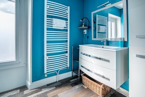 a blue bathroom with a sink and a mirror at Le Vincennes, simple et atypique ! in Cholet