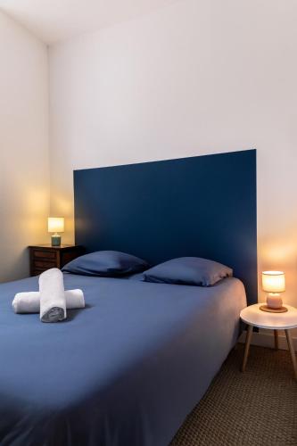 a bed with a blue head board and two pillows at 2 Chambres, Les Dentellières de la Cathédrale in Troyes