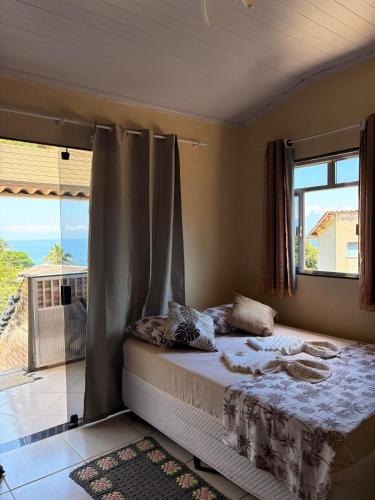a bedroom with a bed with a view of the ocean at Suítes Carla e Carol in Praia de Araçatiba