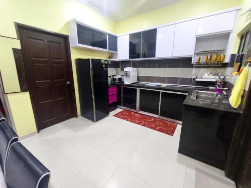 eine Küche mit schwarzen Schränken und einer schwarzen Tür in der Unterkunft Dreamy Stay Penang in Butterworth