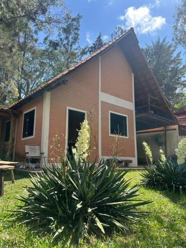 a small brick house with a grass yard at Chalés Moinho in Carrancas