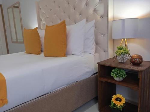 a bedroom with a bed with white sheets and orange pillows at Travellers paradise in Palatswe