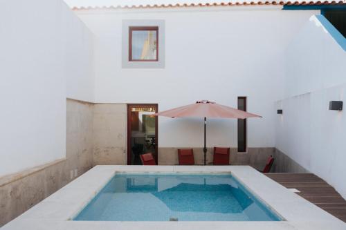 a swimming pool with an umbrella and a table with an umbrella at Casa do Outeiro com vista para o Castelo de Marvão in Marvão