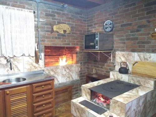 a kitchen with a brick wall with a fireplace at Cabana da Serra in Riozinho