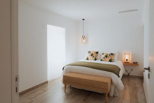 a white bedroom with a bed and a wooden floor at Casa do Outeiro com vista para o Castelo de Marvão in Marvão