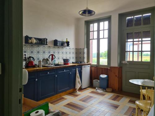 a kitchen with blue cabinets and a table and a window at Maison Huitlala in Lavaufranche