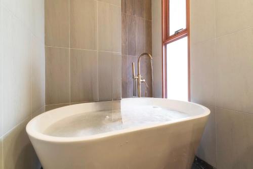 een wit bad in een badkamer met een raam bij Yoo Pool Villa Ranong in Ban Lum Than