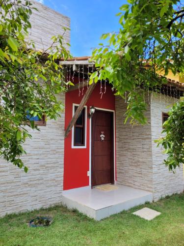 een rode deur op een bakstenen gebouw bij Pousada Jeito Bom de Viver in Caraíva