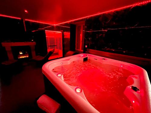 een badkamer met een rood bad met rood licht bij Redroom, Spa, Sauna, cheminée, romantique pour 2 in Quimperlé
