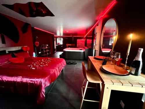 een rode kamer met een bed en een tafel met een spiegel bij Redroom, Spa, Sauna, cheminée, romantique pour 2 in Quimperlé