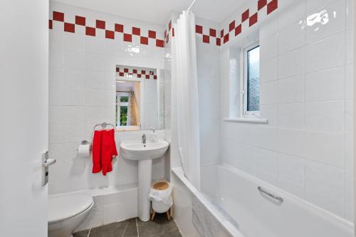 a white bathroom with a sink and a tub and a toilet at 5 Rushbrooke Hotel Apartments Cobh County Cork in Cobh