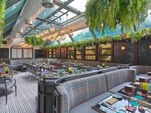 a restaurant with tables and chairs and plants at Pullman Singapore Orchard in Singapore