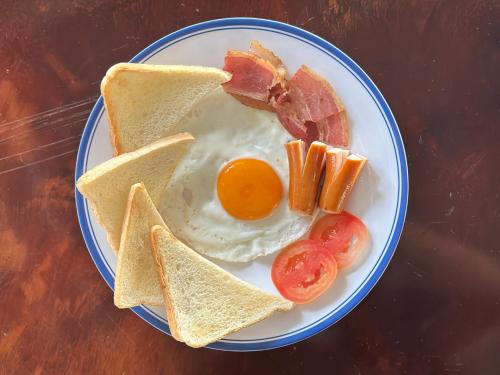 a plate of breakfast food with eggs bacon and toast at บ้านร่มไทร Ban Romsai Nadoem Suratthani in Ban Don Yung