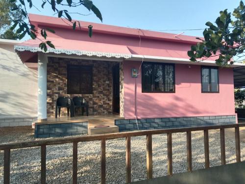 een roze huis met een hek ervoor bij Holidays Homestay Vagamon in Vagamon