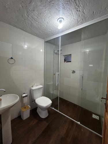 een badkamer met een douche, een toilet en een wastafel bij Gamboa House in Garopaba