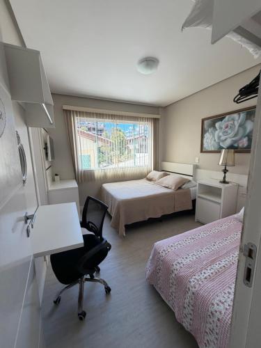 a bedroom with two beds and a desk and a desk at 4 ILHAS, 2 SUITES, 2 GARAGENS in Bombinhas