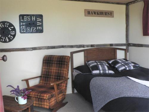 - une chambre avec un lit, une chaise et un panneau dans l'établissement The Old Shepherd, à Masterton