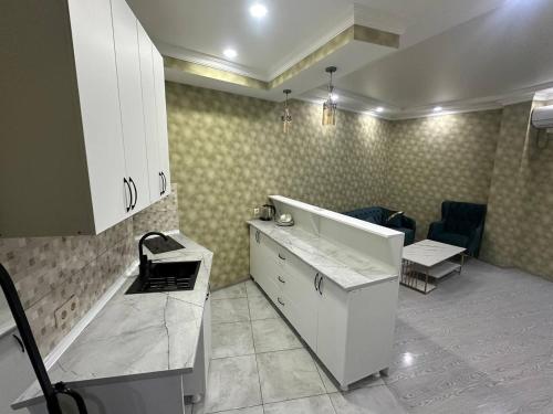 a kitchen with white cabinets and a table and a couch at Hotel Horizont! in Batumi