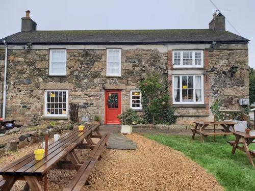 a stone house with a red door and picnic tables at The Pirate Inn in Newlyn