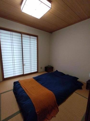 a bedroom with a bed in a room with windows at Tsurumi Green Base 2LDK in Osaka