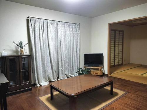a living room with a coffee table in front of a window at Tsurumi Green Base 2LDK in Osaka