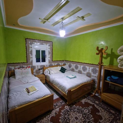 two beds in a room with green walls at Auberge Cascade Imilchil in Imilchil