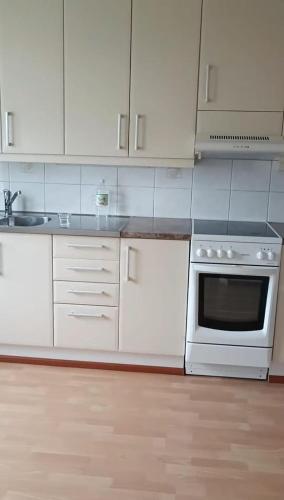 een keuken met witte kasten en een kookplaat oven bij Simple Cozy House in Raahe
