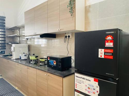 a kitchen with a black microwave on a counter at Che Nat Che Nor Homestay in Kuala Terengganu