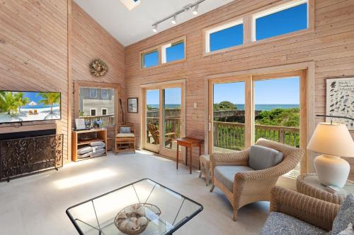 a living room with a fireplace and a view of the ocean at 1222 - Asher in Corolla