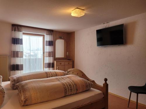a bedroom with two beds and a television on the wall at Haus Steinacher in Hopferau