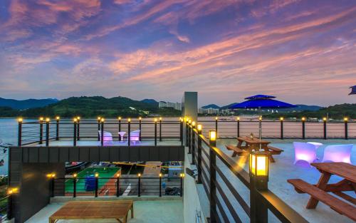 a balcony with a view of the water at night at Onda D'oro Hostel in Yeosu