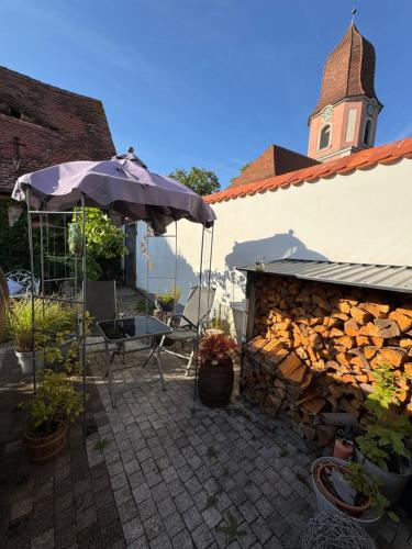 een patio met een tafel en een parasol en een gebouw bij Schlafen im Weinfass in Ipsheim