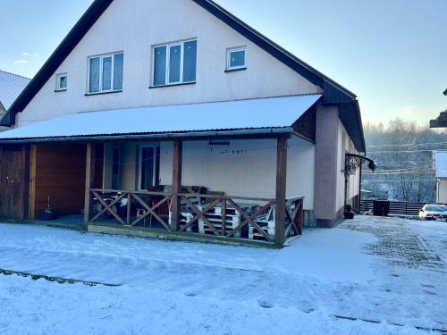 une maison avec une clôture en bois dans la neige dans l'établissement У Лариси, à Solochyn