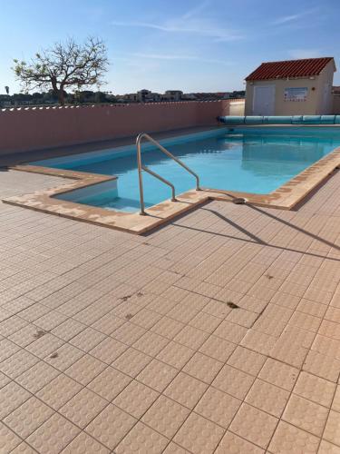 a swimming pool with a hand rail on a tile floor at Studio cabine barcares in Le Barcarès