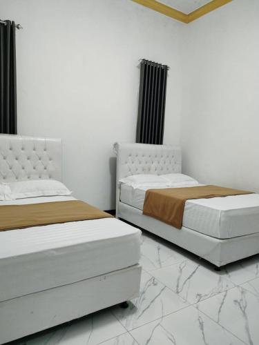 zwei nebeneinander stehende Betten in einem Schlafzimmer in der Unterkunft Victoria Homestay in Pulau Lutung