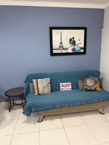 een blauwe bank in een kamer met een foto aan de muur bij Mariscal 2 quartos 3 banheiros -SOBRADO AMENDOEIRA in Bombinhas