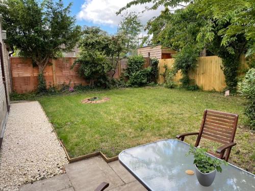 a patio with a glass table and a chair in a yard at Stylish 3BR Cambridge Bungalow, Near Science Park in Cambridge