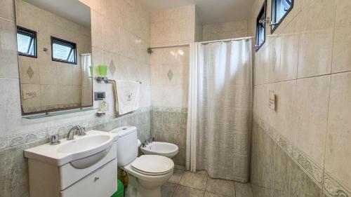 een badkamer met een toilet, een wastafel en een spiegel bij Quinta La Gloria in La Plata