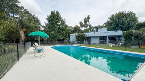 een zwembad met parasol naast een huis bij Quinta La Gloria in La Plata