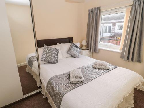 a bedroom with a bed with a mirror at Primrose Cottage in Chathill