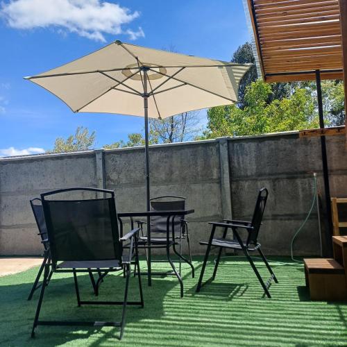 een tafel en stoelen en een parasol op een patio bij Refugio las Mariposas Chillán in Chillán