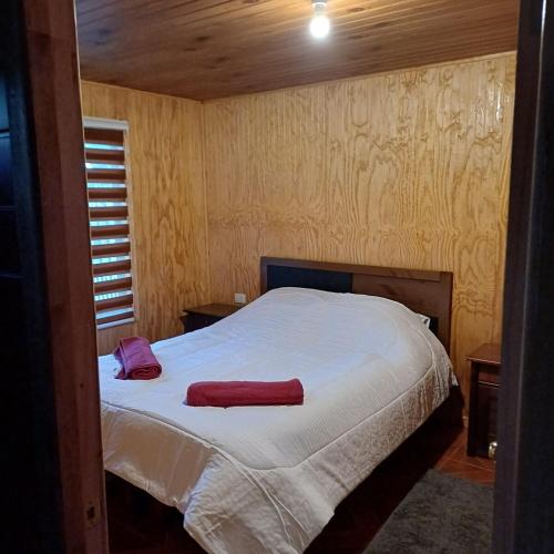 a bedroom with a bed with white sheets and red towels at Refugio las Mariposas Chillán in Chillán